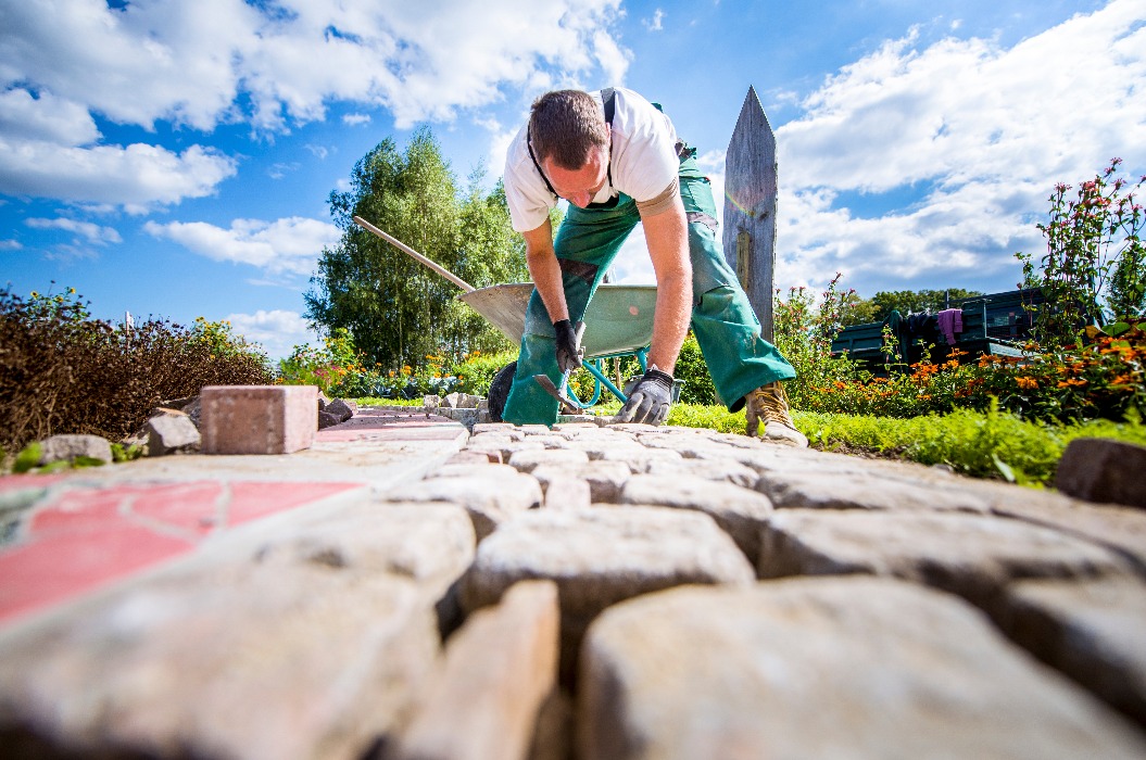 Handwerker verlegt Pflastersteine in einer Gartenanlage